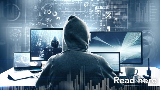 hacker surrounded by computer screens and code. Click here to read article